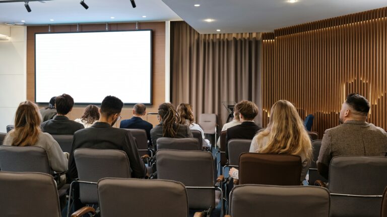 IAM-konferenssin osallistujia salissa seuraamassa esitystä.