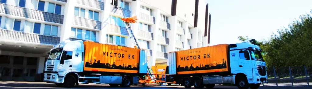 Victor Ek -muuttoyrityksen rekat ja muuttohissi kerrostalon edessä